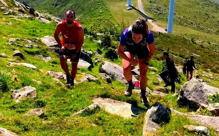 Corredores subiendo una cresta con los aerogeneradores del Oiz al fondo, dorsal 63 en primer plano