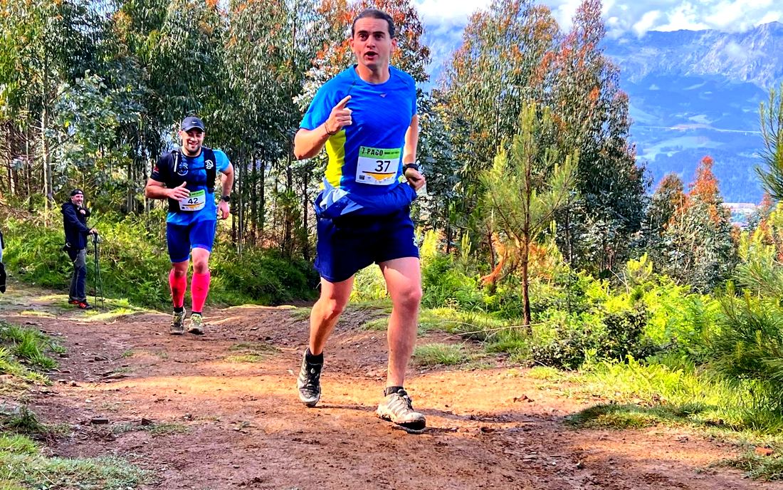 Corredor con dorsal de la 7 Pago dando el pulgar hacia arriba en un tramo de bosque, con otro corredor detrás y las montañas al fondo, dorsal 37