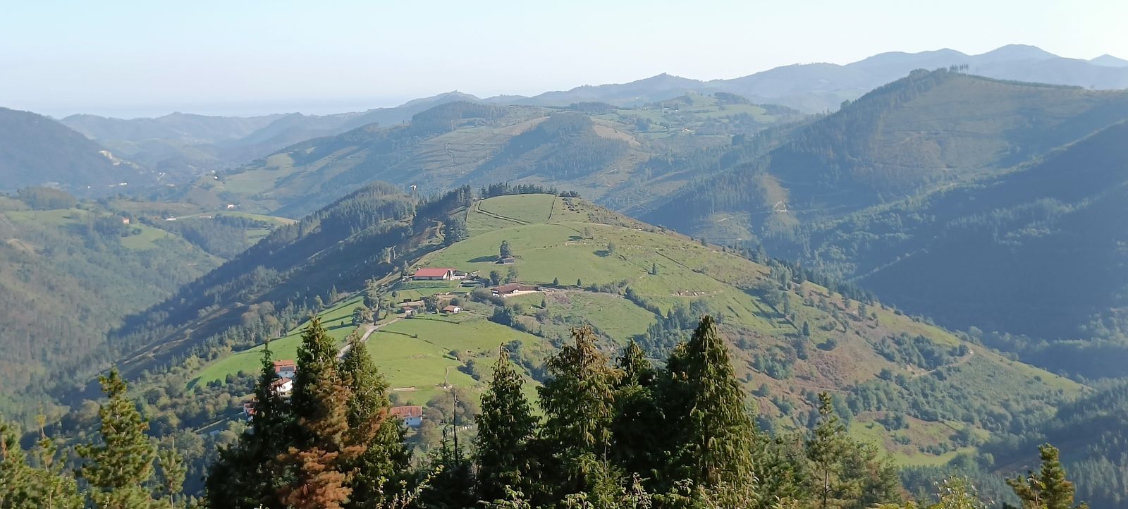 Vista panor&aacute;mica de un valle con caser&iacute;os, monta&ntilde;as y el mar al fondo