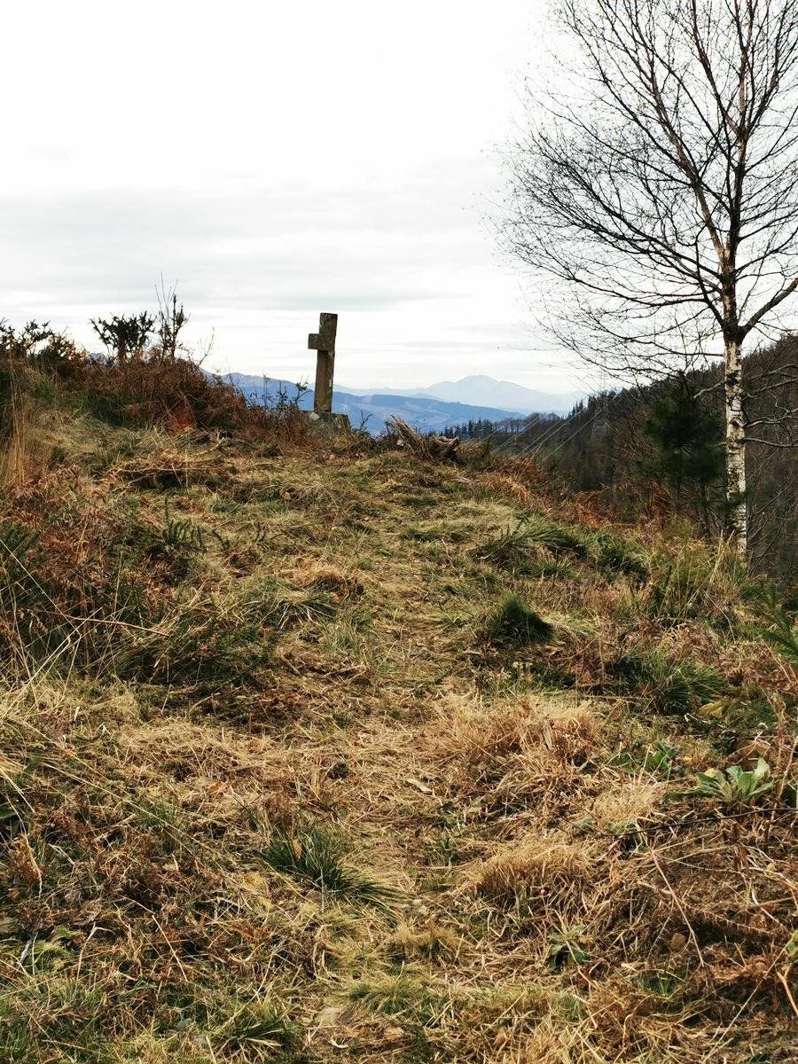 Una cruz en uno de los altos de la ruta, entre hierba seca y con vistas a un monte al fondo
