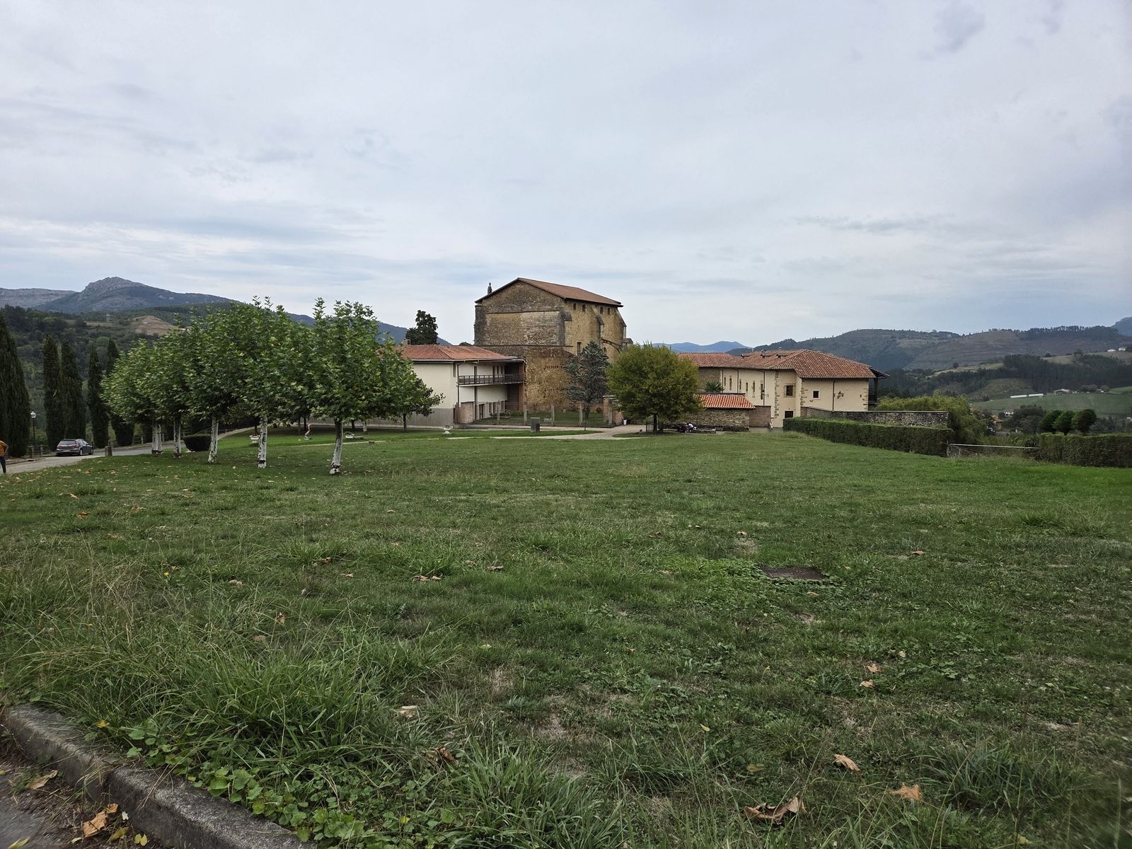 Zenarruzako monasterioa zuhaitzak dituen zelai baten atzean, mendiak atzealdean