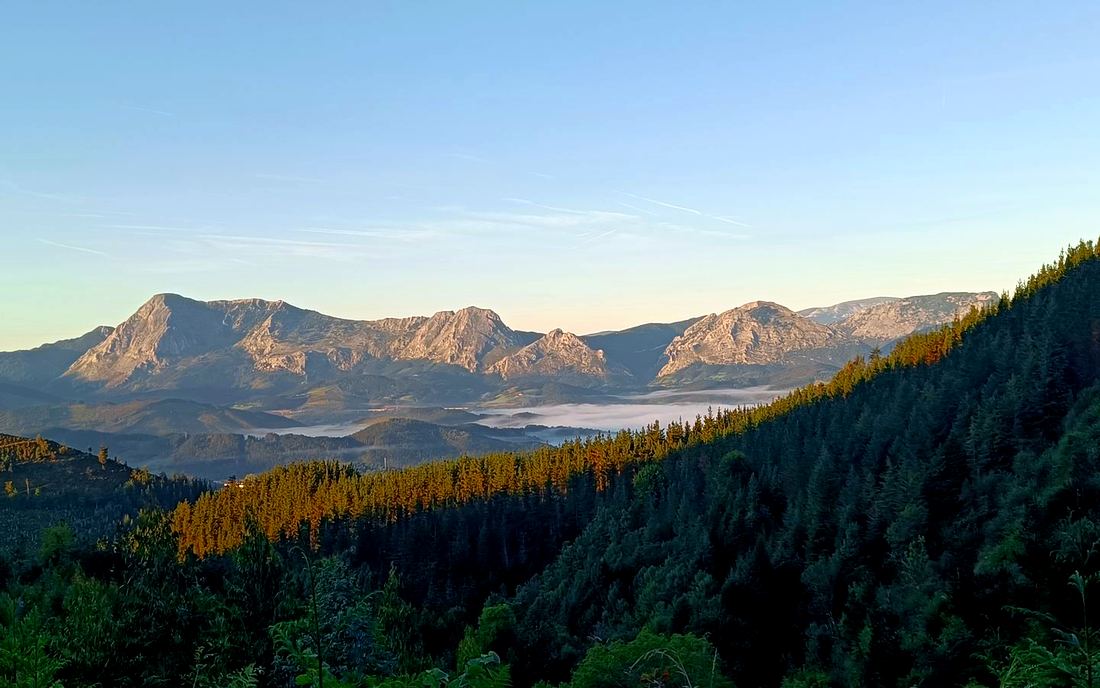 Cordillera montañosa en silueta al amanecer, con niebla en el valle