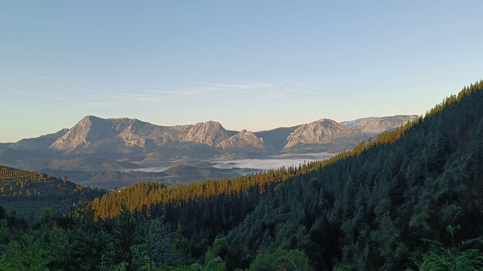 Cordillera monta&ntilde;osa en silueta al amanecer, con niebla en el valle