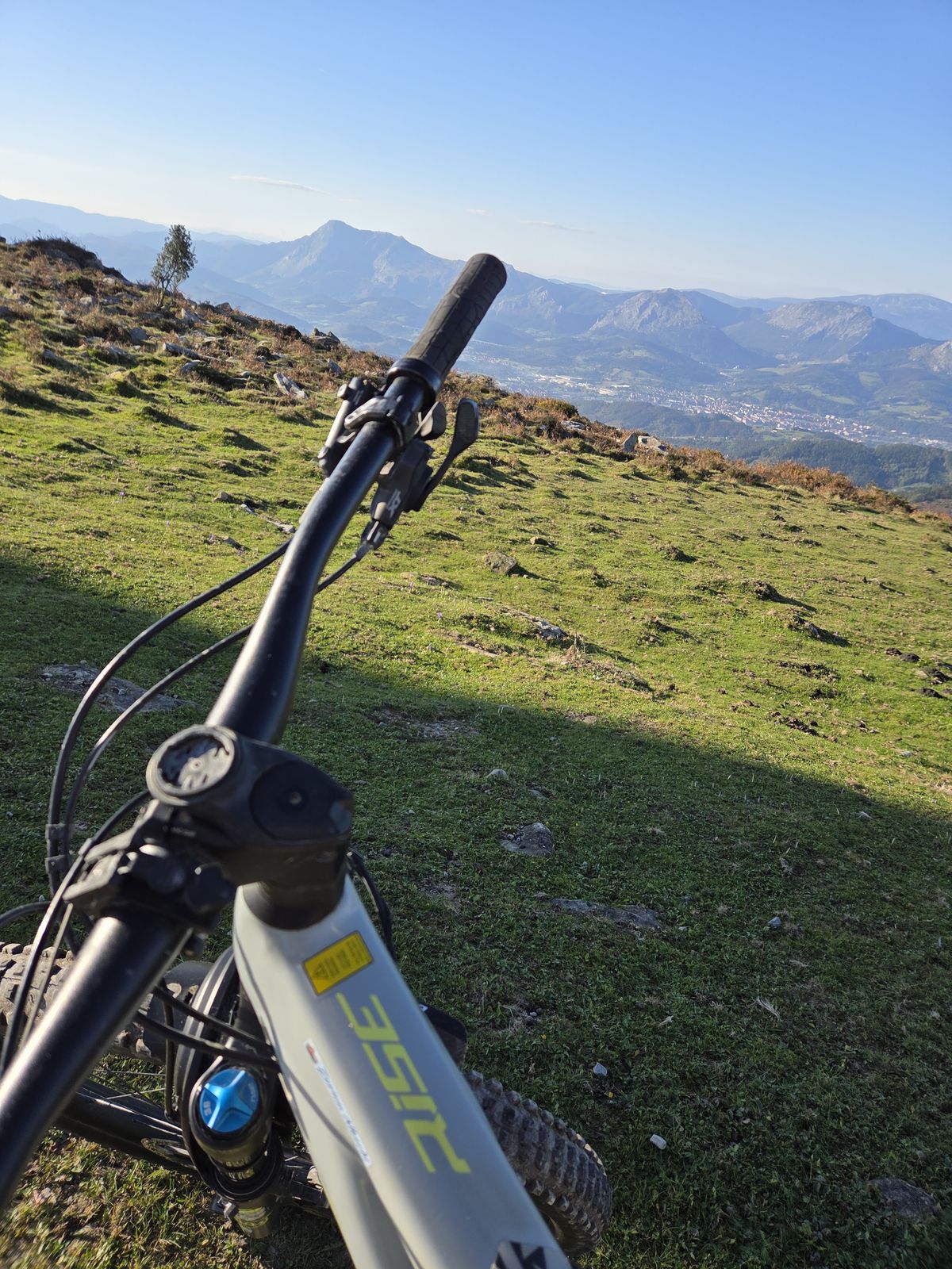 Manillar de la e-bike con las monta&ntilde;as y el pueblo al fondo