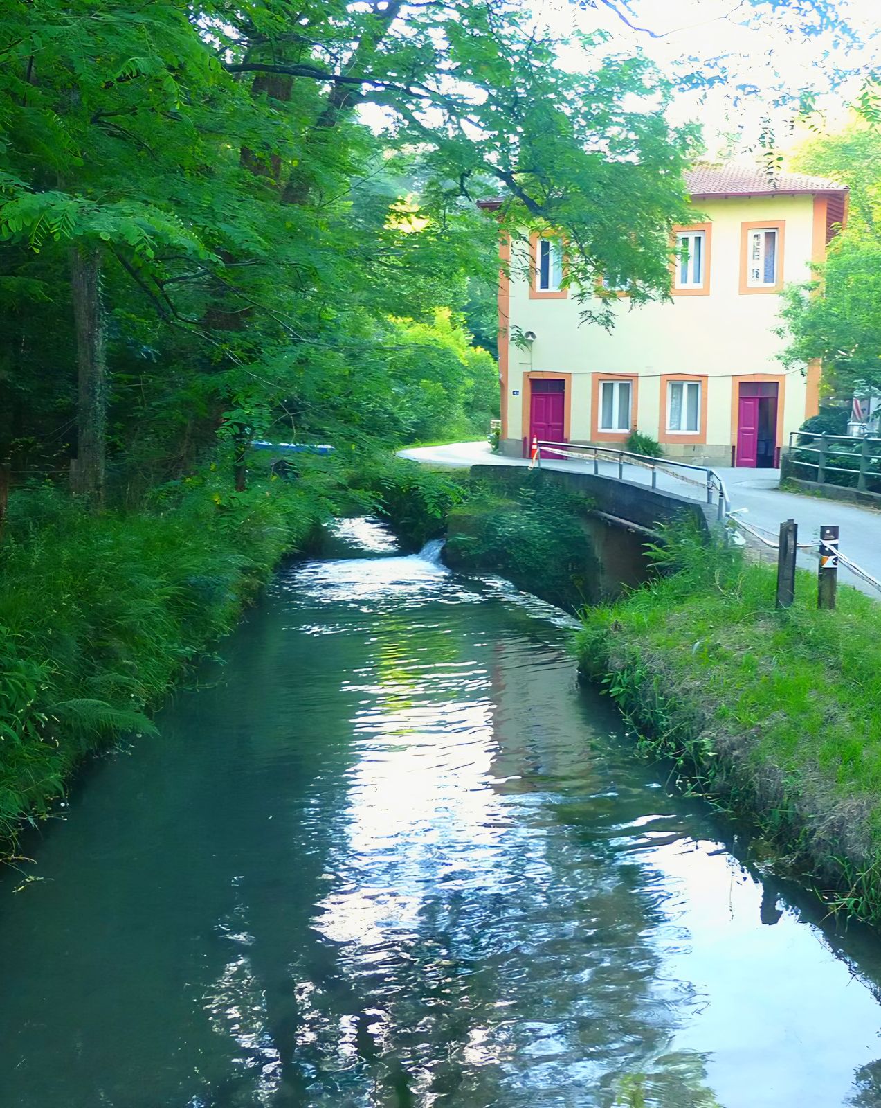 Canal de la Central Patala, con el edificio de la central y un puente de piedra al fondo