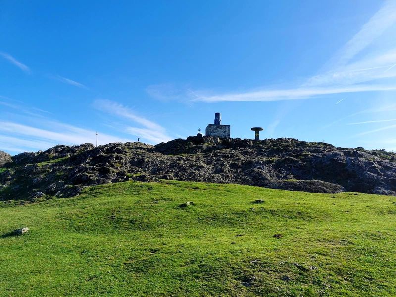 Construcci&oacute;n de piedra y hormig&oacute;n en una cima rocosa, bajo un cielo despejado