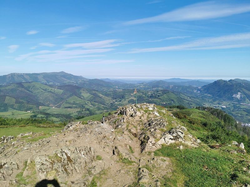 V&eacute;rtice geod&eacute;sico en una cima rocosa, con amplias vistas a las monta&ntilde;as del entorno y aerogeneradores al fondo