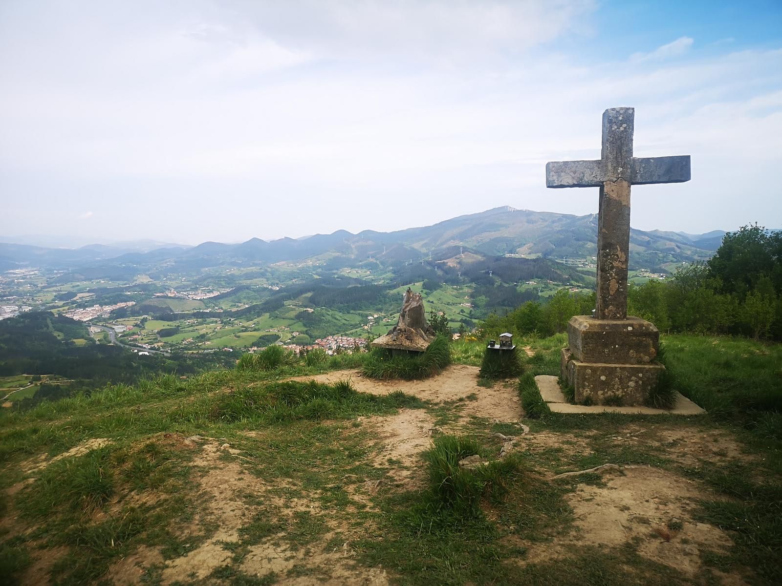 Cruz de piedra en un mirador de Santama&ntilde;esar, con el valle y los caser&iacute;os al fondo