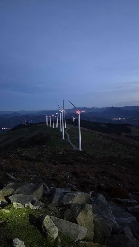 Oizko parke eolikoaren aerosorgailuak ilunabarrean, harrietatik ikusita