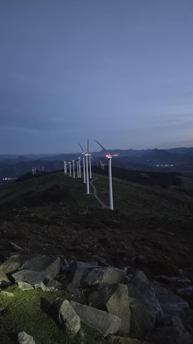 Oizko parke eolikoaren aerosorgailuak ilunabarrean, harrietatik ikusita