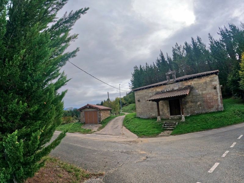 Ermita de piedra junto al cruce de la carretera, con la pista que sale a su izquierda