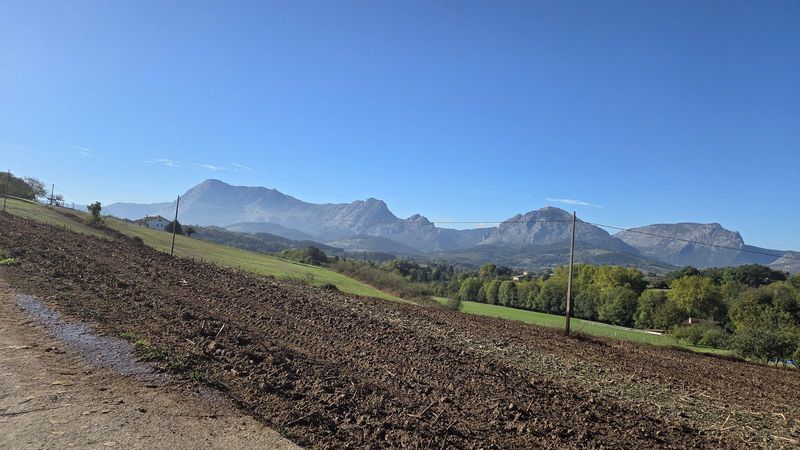 Campo reci&eacute;n arado junto a la pista, con las monta&ntilde;as del entorno al fondo