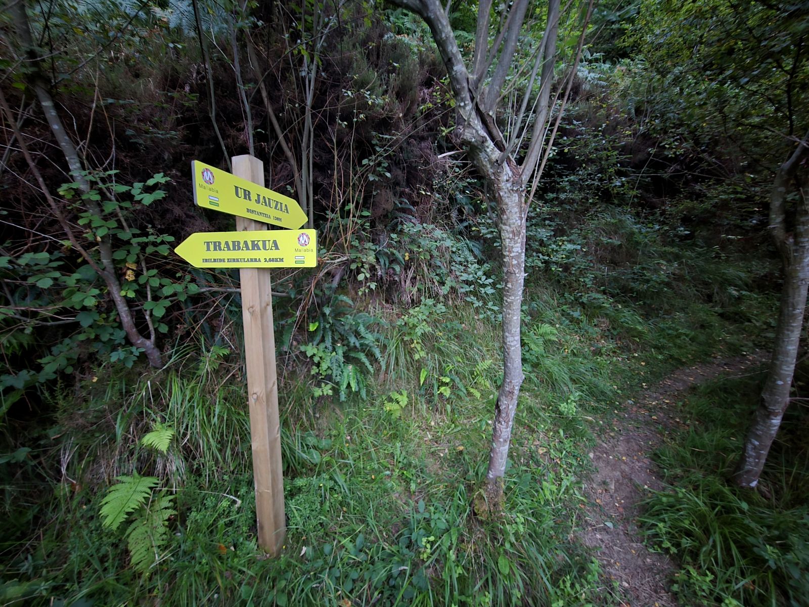 Cartel de madera del recorrido, con indicaciones a Ur Jauzia y a Trabakua