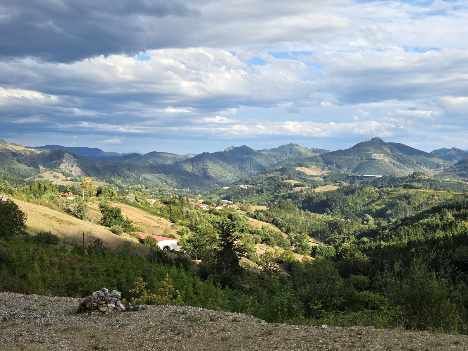 Vistas al atardecer sobre los valles y montes del entorno, con un mont&oacute;n de piedras en primer plano