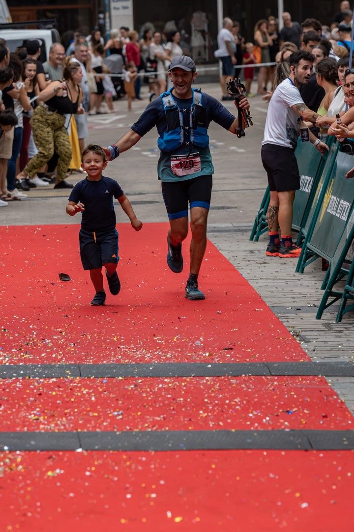 Llegada a meta por la alfombra roja entre confeti, de la mano de un ni&ntilde;o, con el p&uacute;blico animando a los lados
