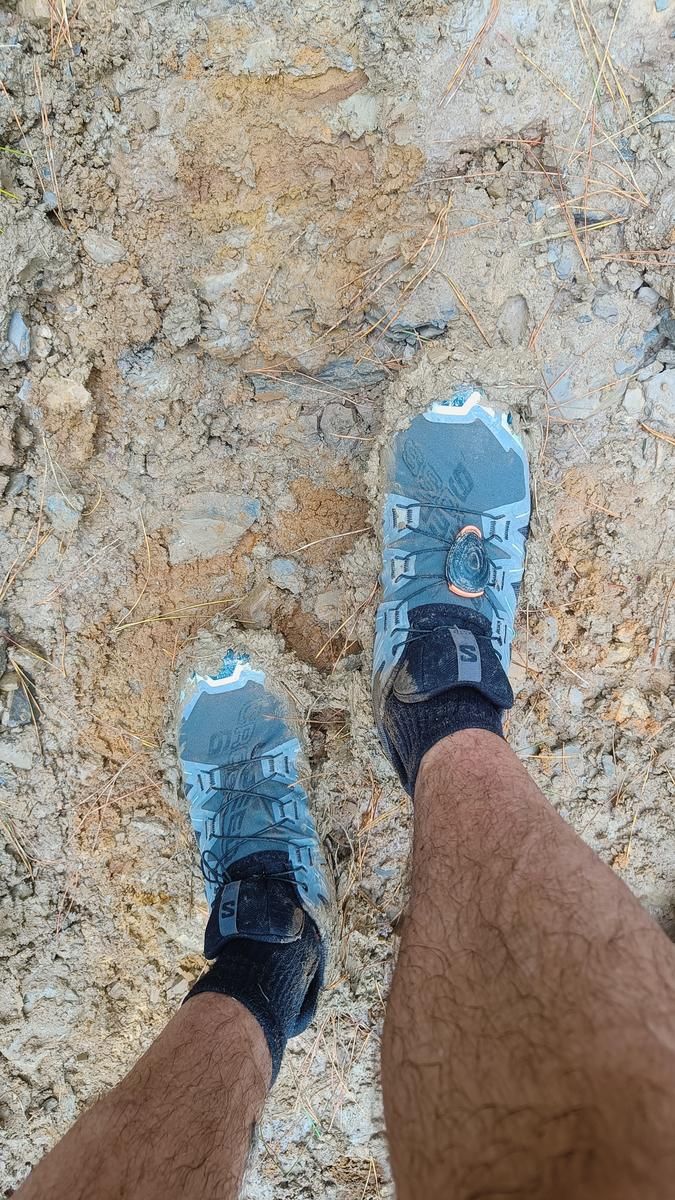 Zapatillas de trail sobre el barro seco y agrietado de una rampa muy empinada, vista desde arriba
