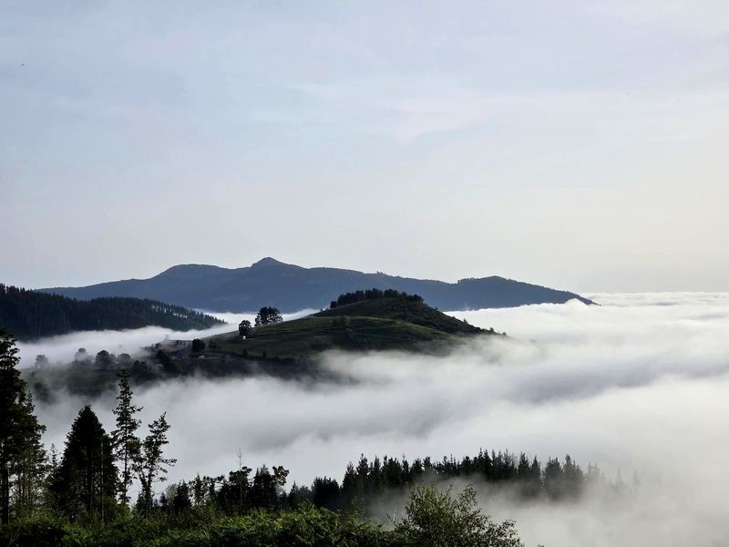 Vista panorámica desde la ruta, con el valle cubierto de niebla y las crestas del Duranguesado al fondo