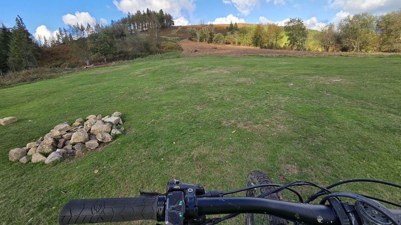 Zelaia harri-pila batekin eta gailurrerako igoera hondoan, e-bikearen eskulekutik