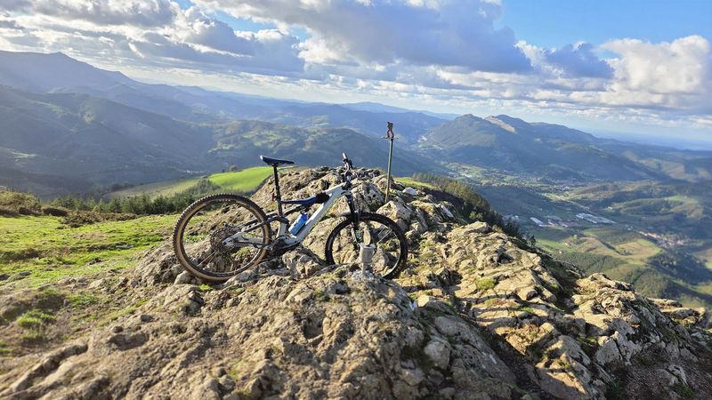 E-bikea Kalamuako gailurreko harkaitzetan bermatuta, mendiak eta harana hondoan