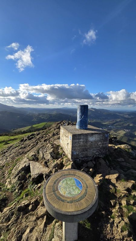 Erpin geodesikoa eta orientazio-mahaia Kalamuako gailurrean, mendiak zeru urdinaren azpian
