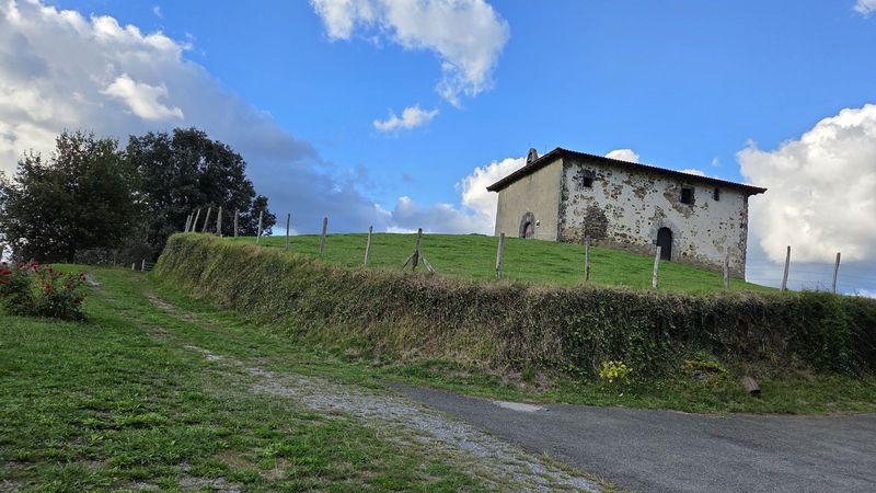 Santa Kruz ermita, harrizkoa eta karez zuritua, zelai baten goialdean bidearen ondoan