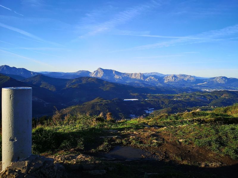 Moj&oacute;n de piedra en la cima, con las monta&ntilde;as del entorno y un pueblo en el valle al fondo