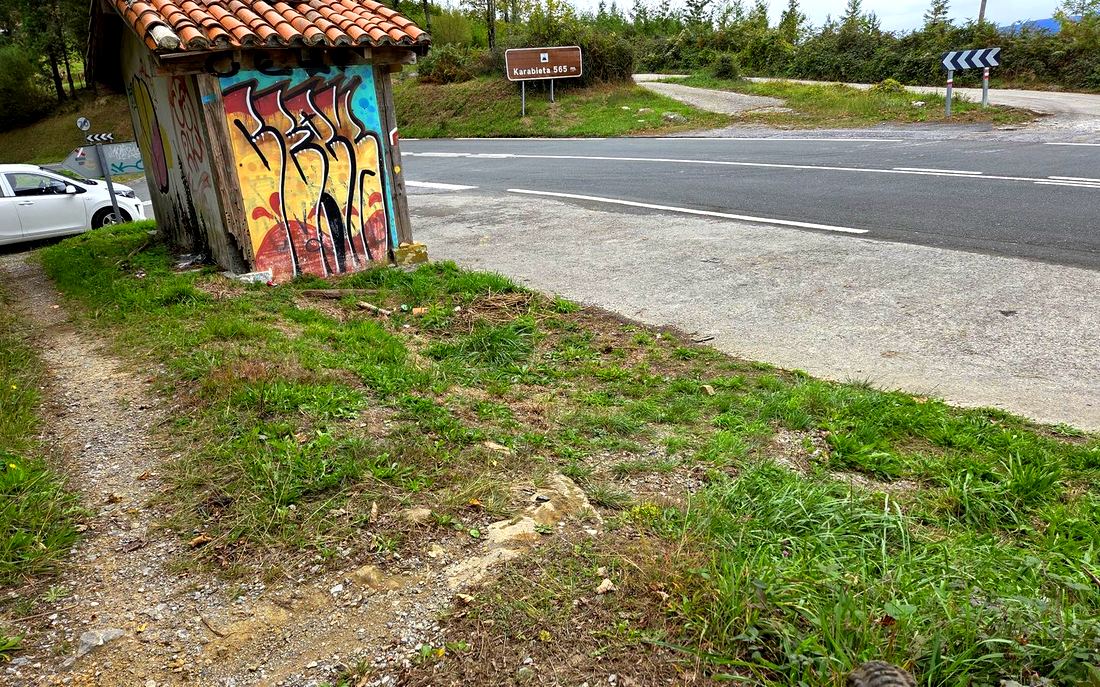El alto de Karabieta, con el cartel de 565 m y una caseta de madera pintada junto al cruce