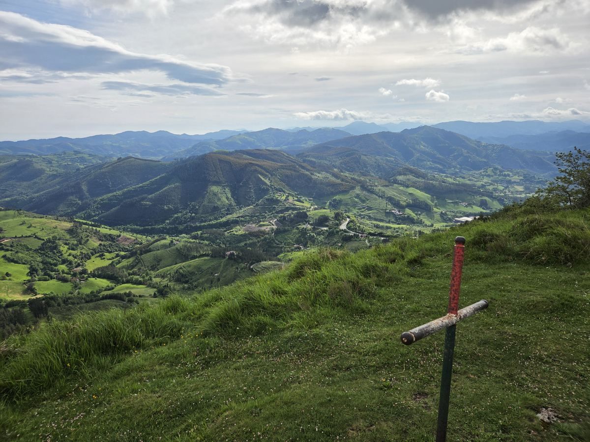 Vista desde un alto sobre los montes de alrededor de Mallabia, con una cruz de madera en primer plano