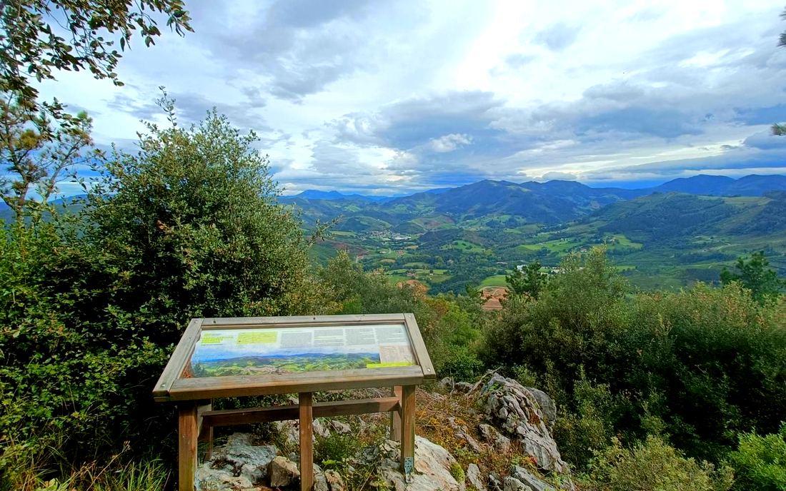 Panel informativo de un mirador con vistas al valle de Markina-Xemein entre nubes