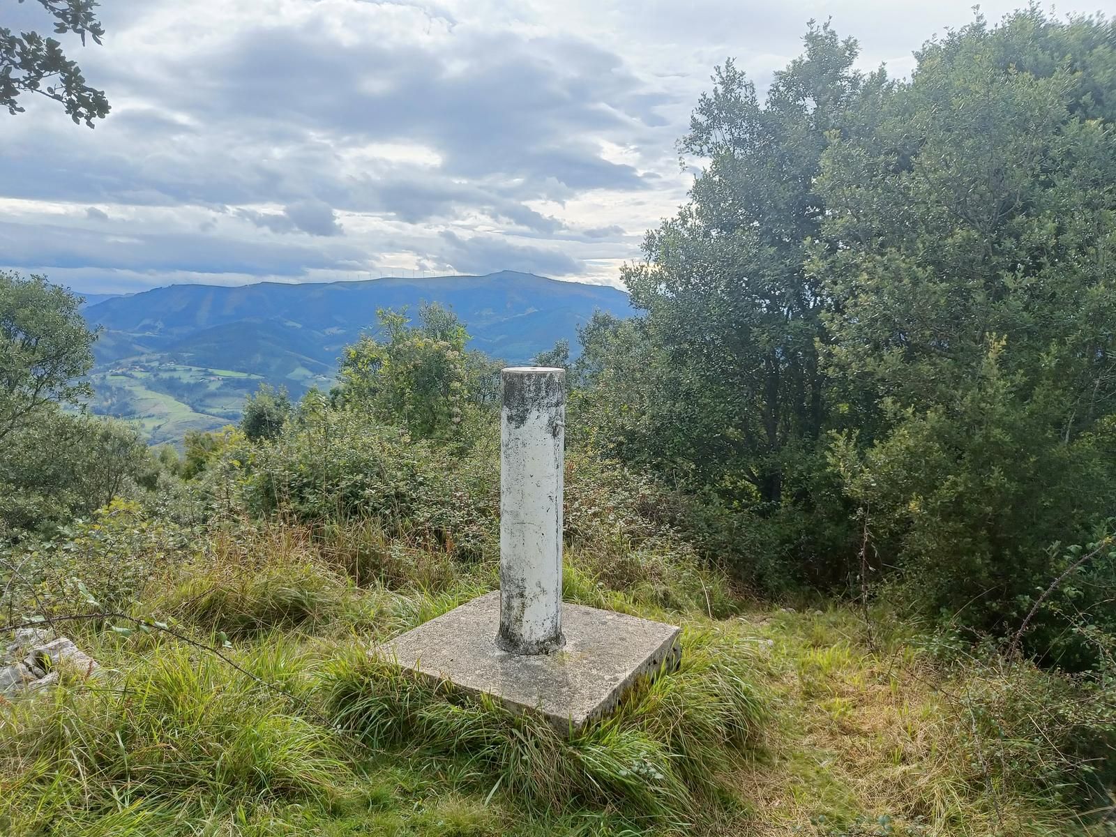 Hormigoizko erpin geodesikoa Zapolako gailurrean, parke eoliko bat hondoan
