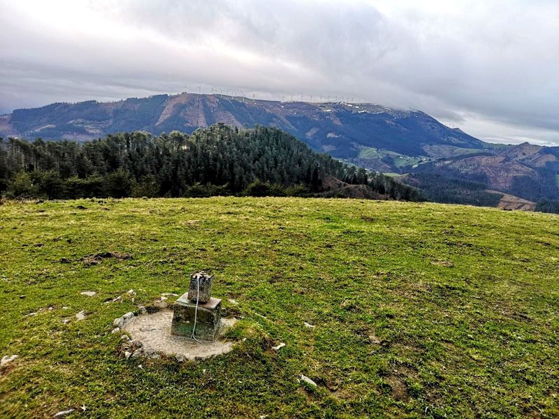 Moj&oacute;n en la cima del Mendibil, con el parque e&oacute;lico y el pueblo al fondo