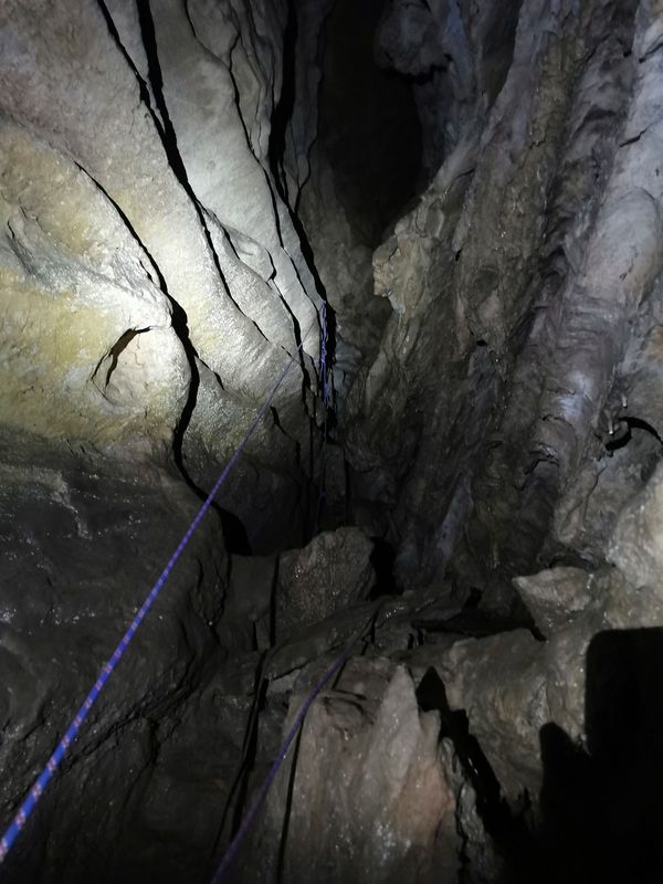 Kobako arrakala bertikal estua, soka more bat harrizko horma bustien artetik jaisten
