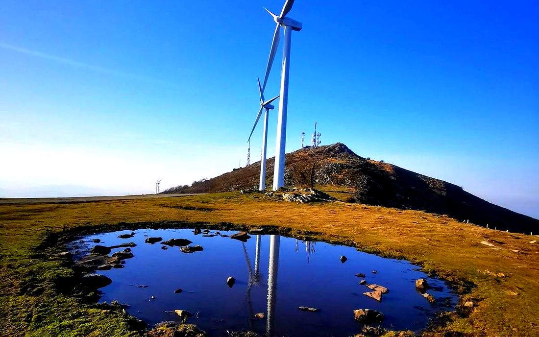 Aerogeneradores del Oiz reflejados en un charco de la cumbre, con las antenas al fondo
