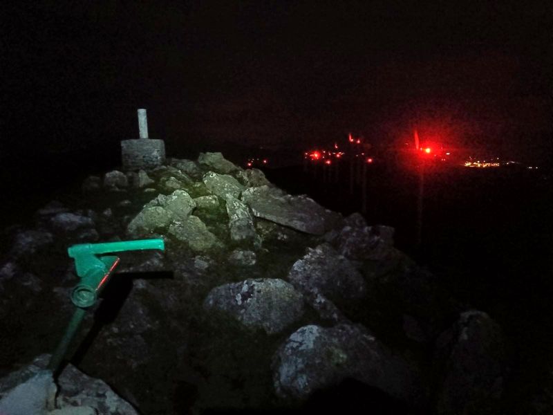 V&eacute;rtice geod&eacute;sico en el Oiz de noche, con las luces rojas de los aerogeneradores al fondo