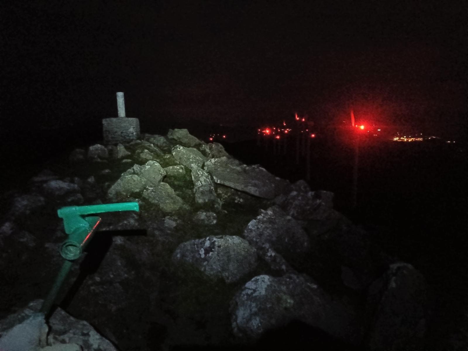 V&eacute;rtice geod&eacute;sico en el Oiz de noche, con las luces rojas de los aerogeneradores al fondo
