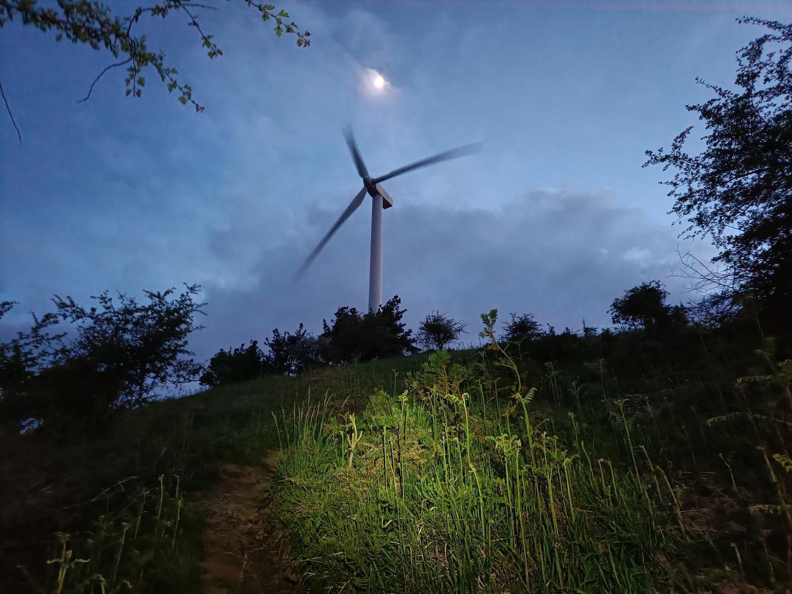 Un aerogenerador del Oiz recortado contra la luna, al anochecer