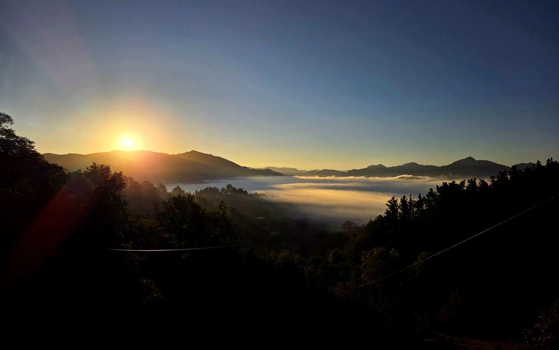 Amanecer con niebla en el valle, con el sol saliendo tras los montes