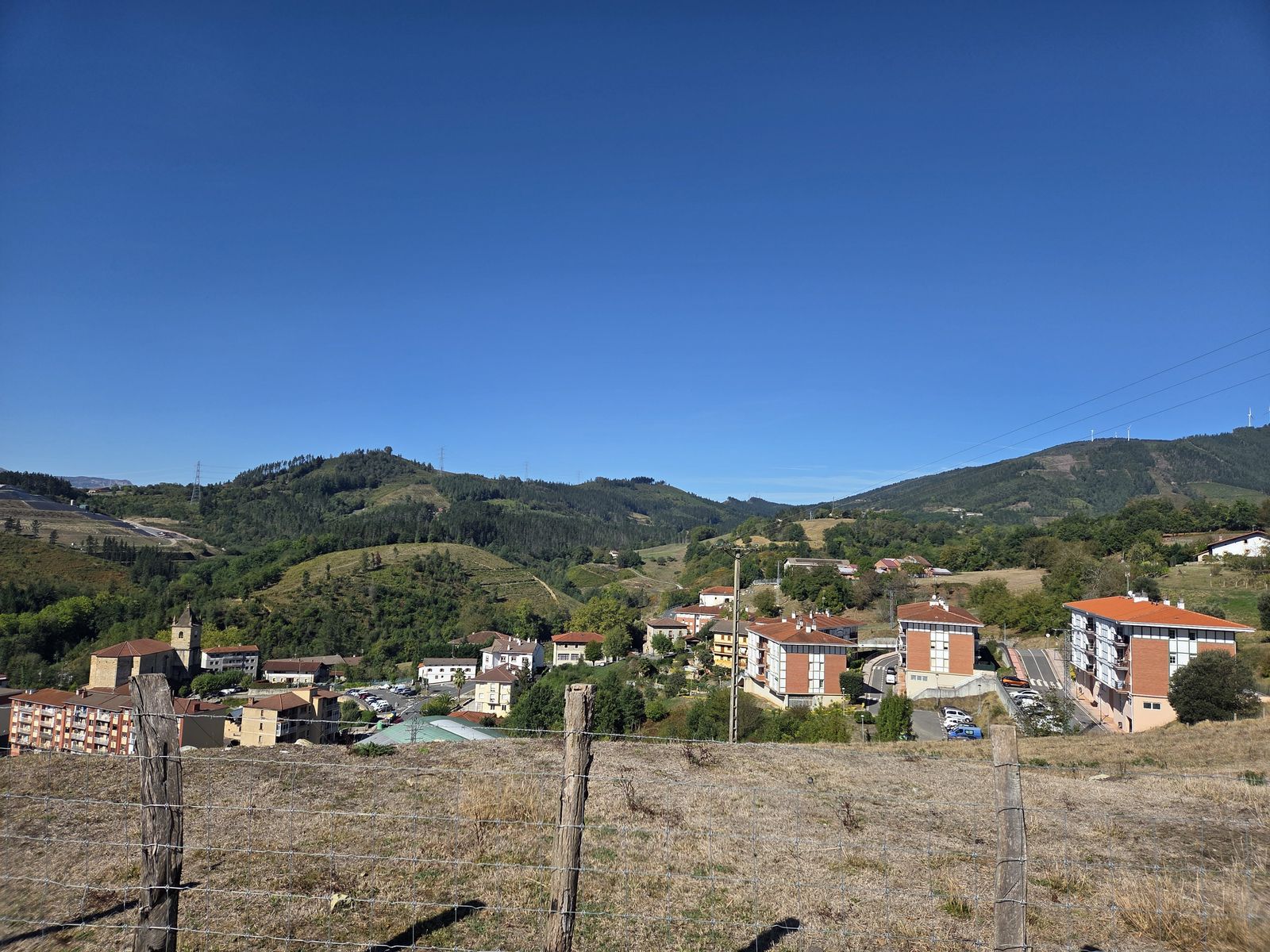 Vista del pueblo con la torre de la iglesia y los tejados rojos, entre los montes