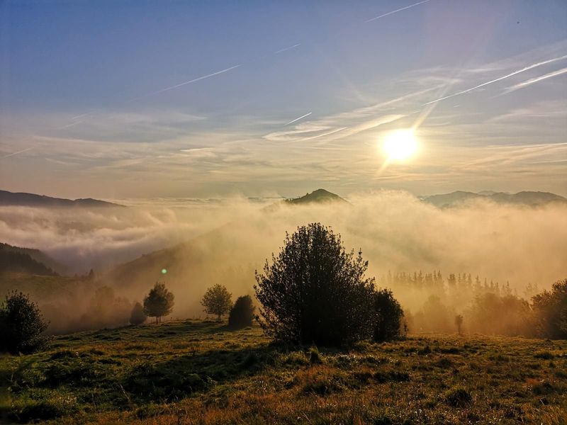 Mar de nubes al amanecer desde la media ladera de Oiz, con el sol bajo iluminando la niebla que llena los valles