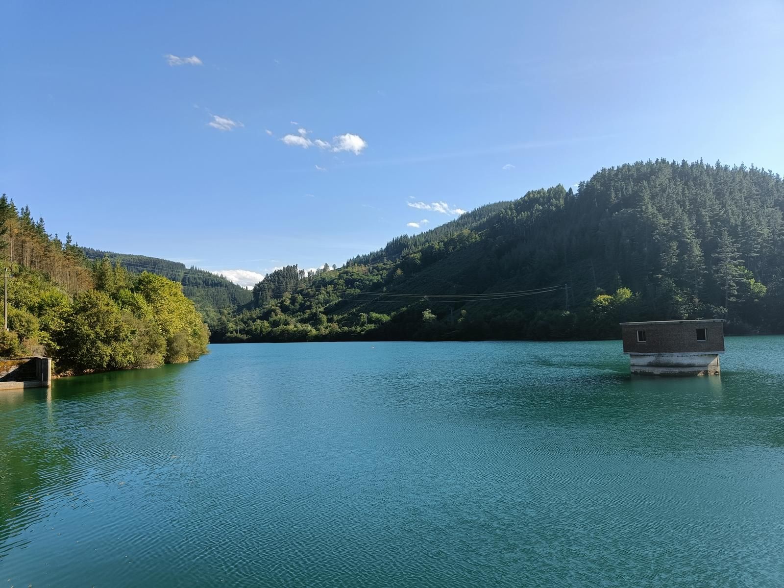 Aixolako presa egun eguzkitsu batean, ur-hartuneko dorrea urtegiaren gainean ageri dela