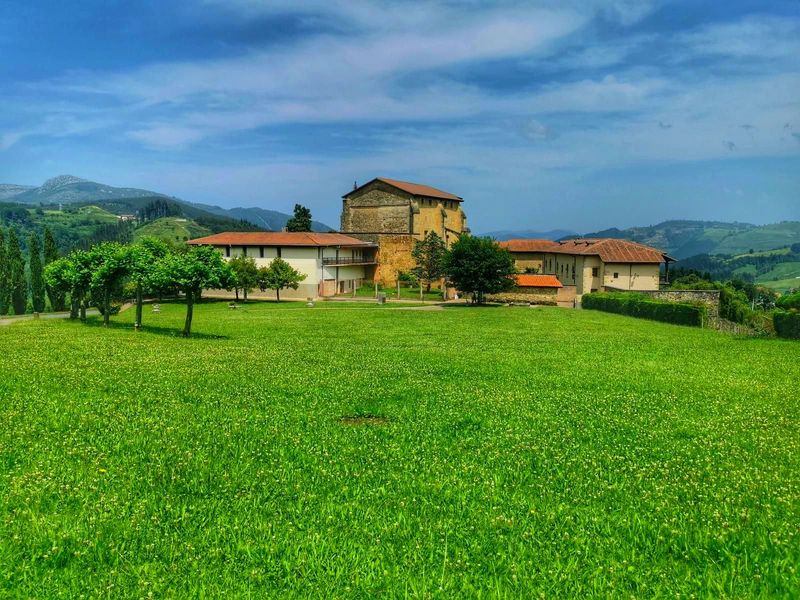 La Colegiata de Zenarruza vista desde el prado, con el caser&iacute;o anexo y los montes al fondo