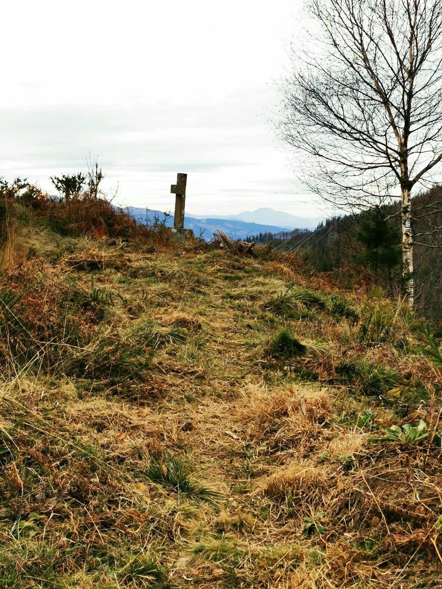 Cruz de madera en la cima, con vistas a las monta&ntilde;as del entorno